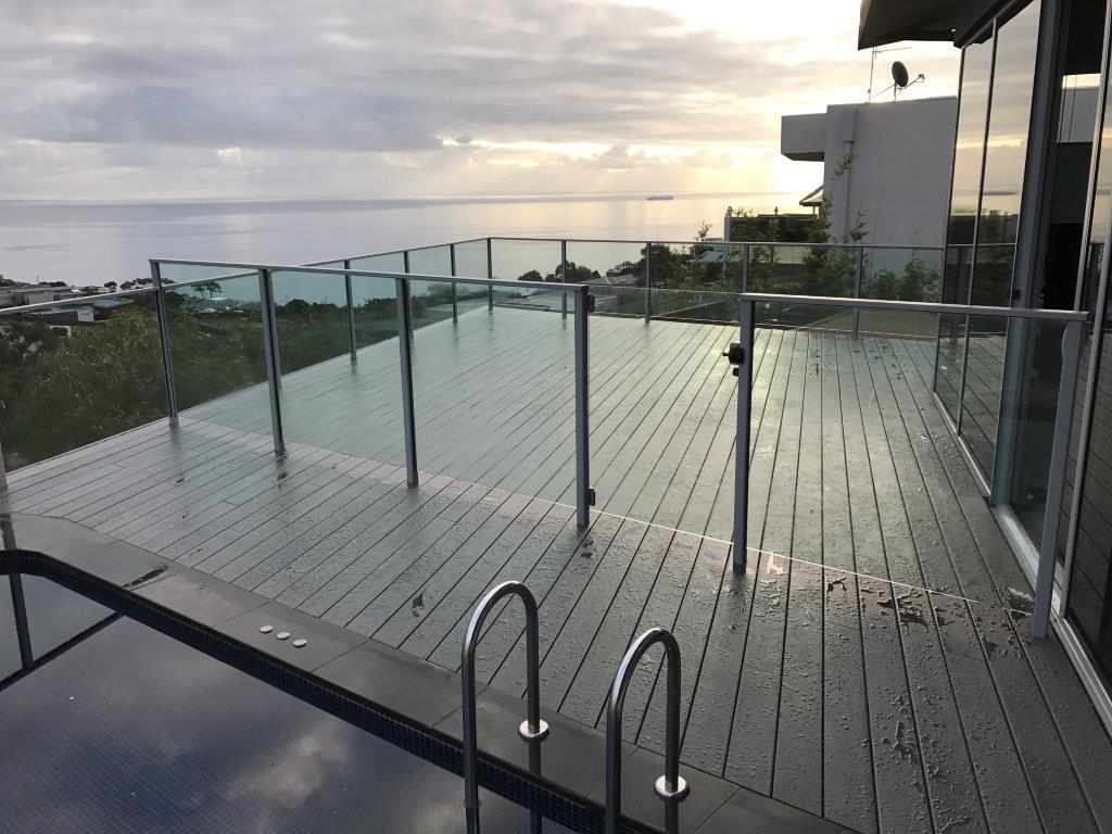 Rooftop timber deck with frameless glass balustrade overlooking Port Phillip Bay at sunset