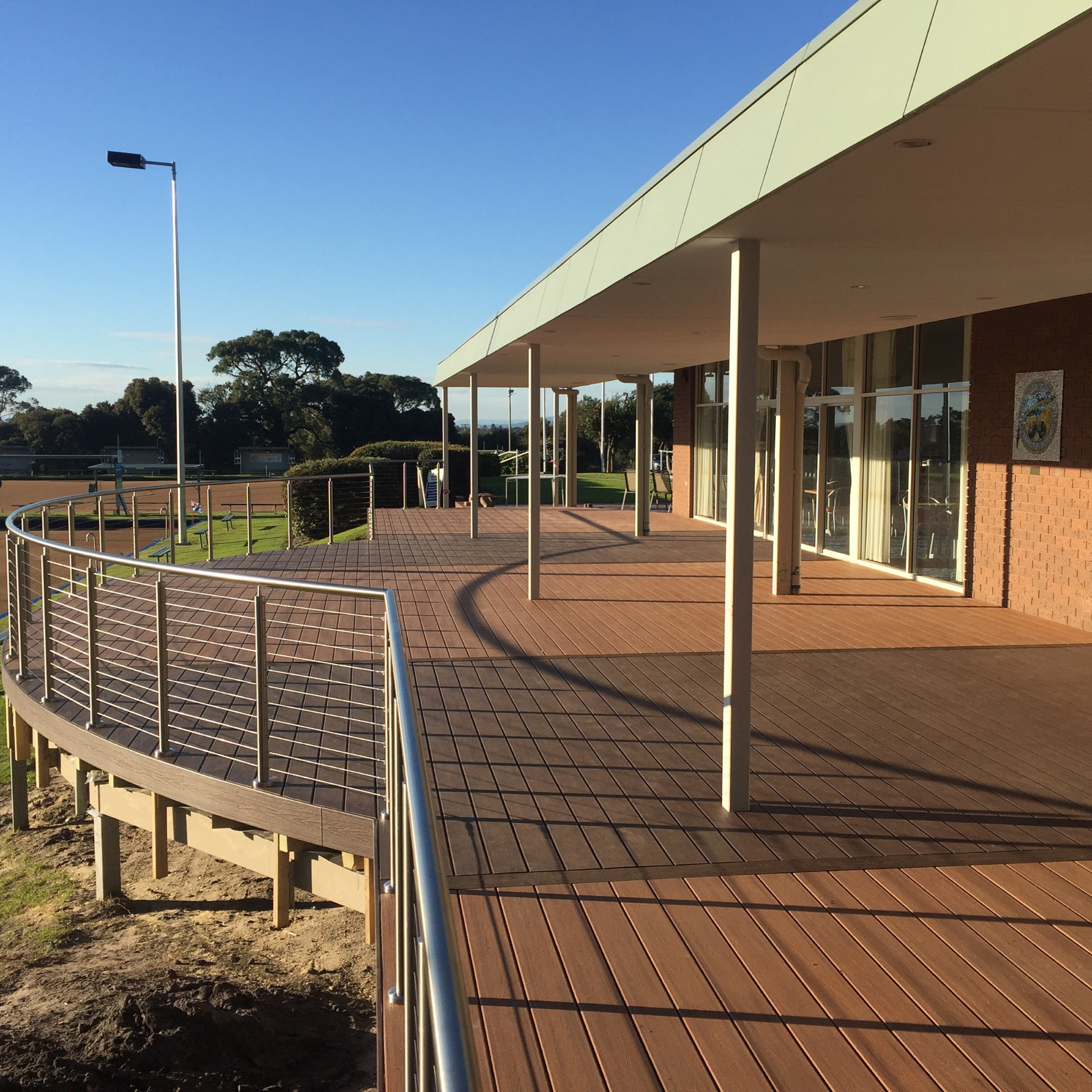 Large commercial verandah deck in two-tone composite with curved stainless balustrade