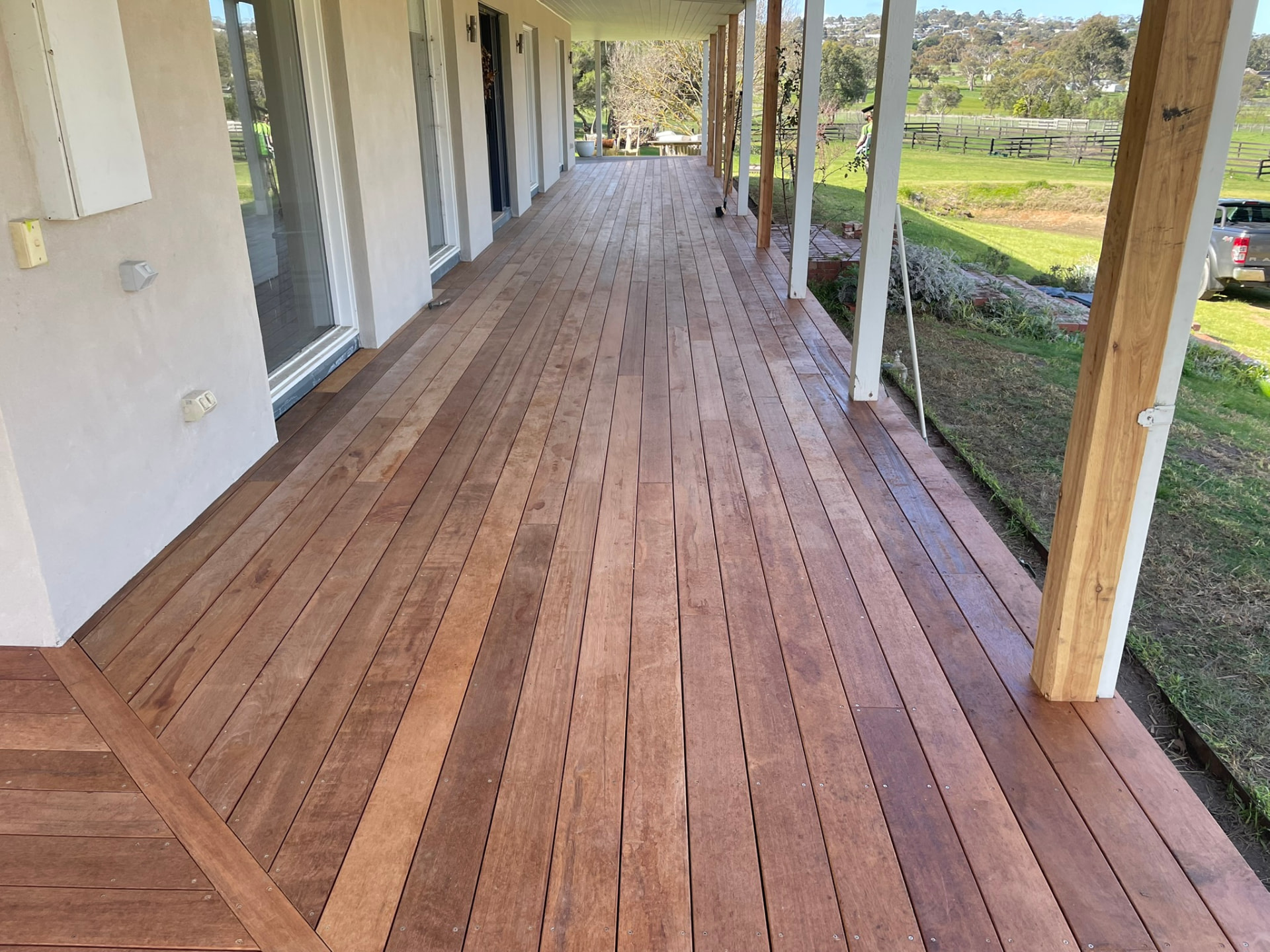 Long wrap-around verandah deck in oiled hardwood beside a country home