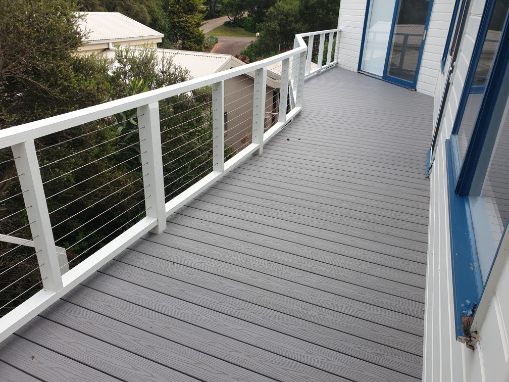 Grey composite cottage deck with white and wire balustrade overlooking coastal bushland